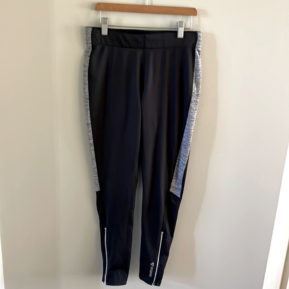 Ankle-length black running leggings with zippers on outside of both legs.